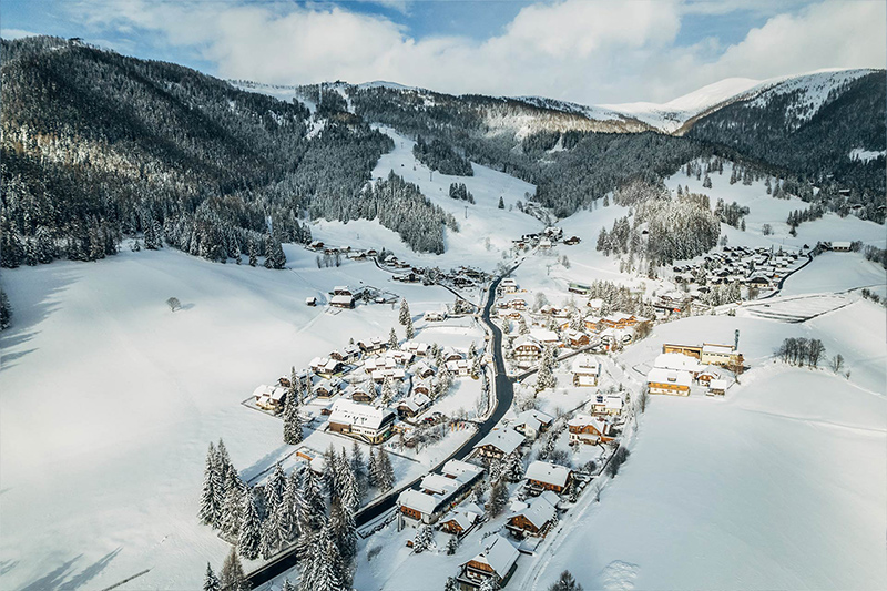 Panorama Bergdorf St. Oswald im Winter mit Blick auf die Nockberge in Bad Kleinkirchheim Kärnten, ideal für Winterurlaub.